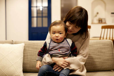 ソファに座り、子どもを後ろから抱きかかえている西連寺さん親子の写真