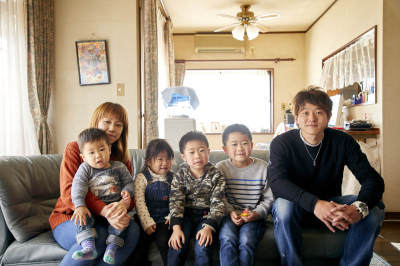 ソファに並んで腰掛けている、横田さんご夫婦、男の子3人、女の子1人の家族写真