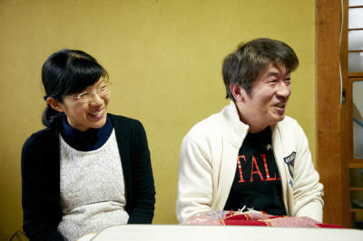 室内でテーブルを前に腰掛けている、笑顔の高橋さんご夫婦の写真