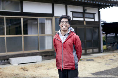 家の前に笑顔で立っている、村田さんの写真